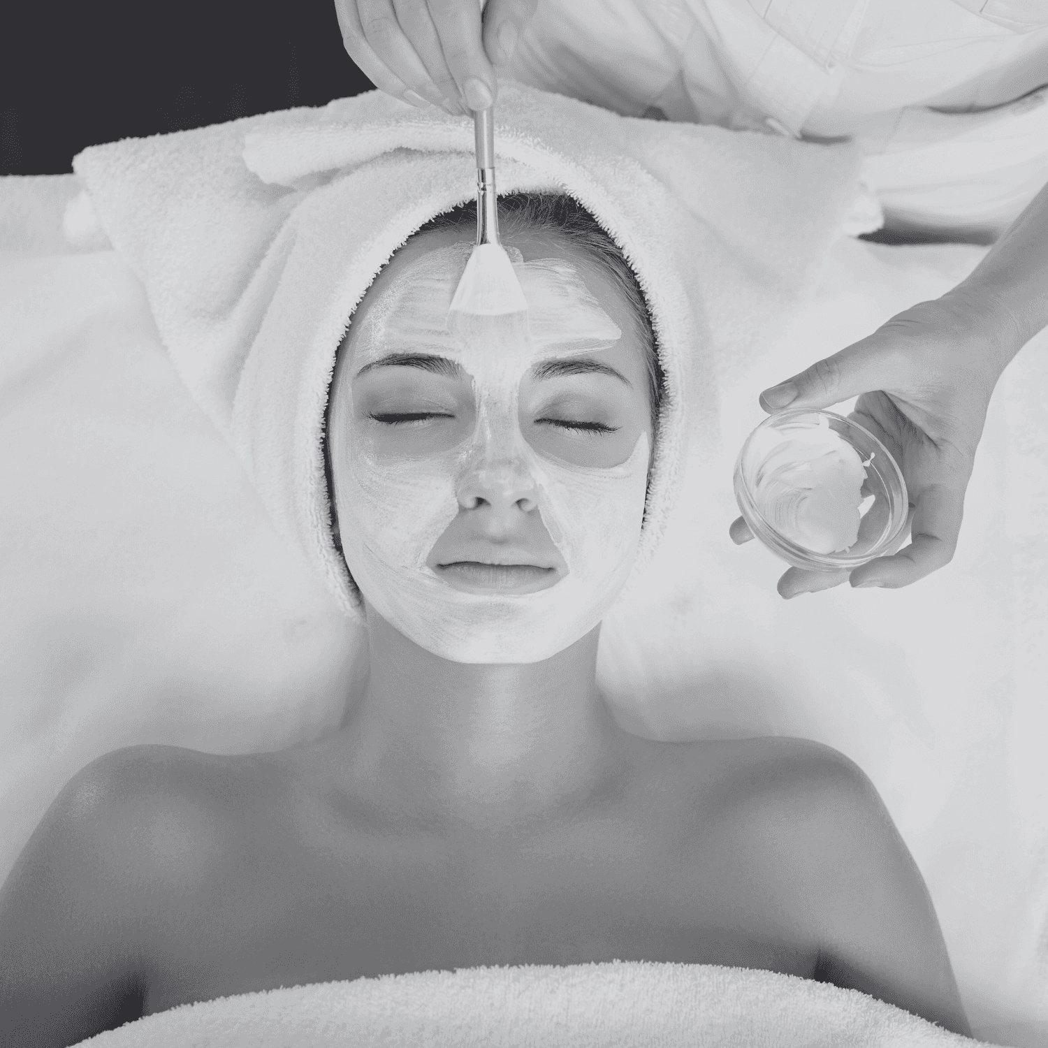 Woman receiving a facial treatment with a brush applied to her face while lying down.